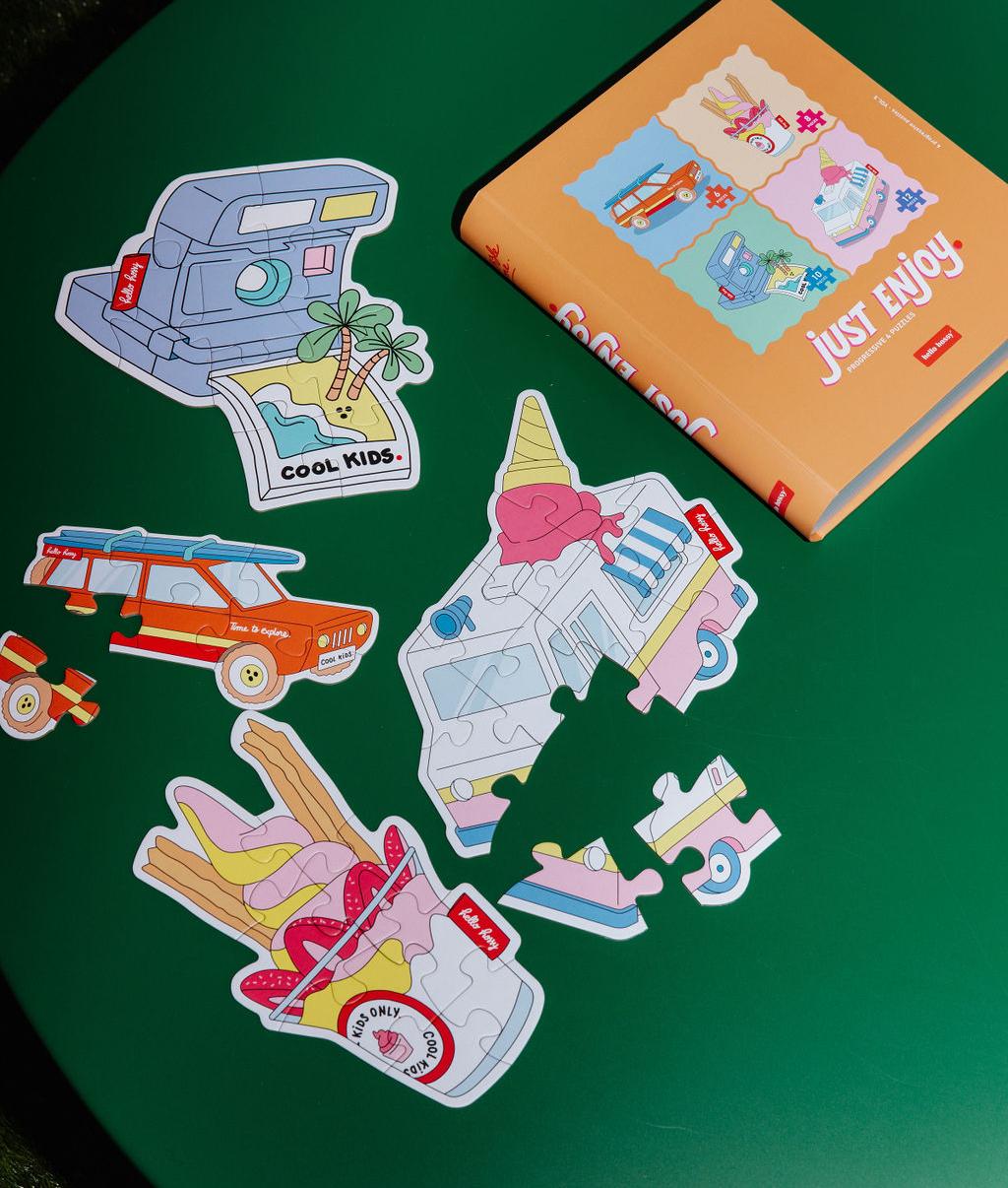 Puzzles colorés "Just Enjoy" partiellement assemblés sur une table avec la boîte à côté - vue du dessus - Hello Hossy