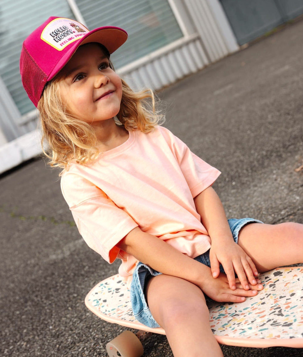 Kind trägt die fuchsiafarbene Cap mit gebogenem Schirm und Hunde-Patch Hello Hossy