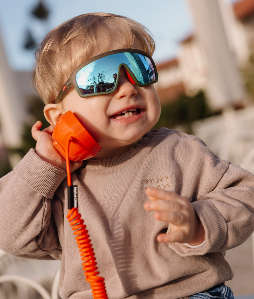 Sonnenbrillen für Kinder Grün Sportliche Gestellform Blau Spiegelglas getragen von einem Baby Hello Hossy