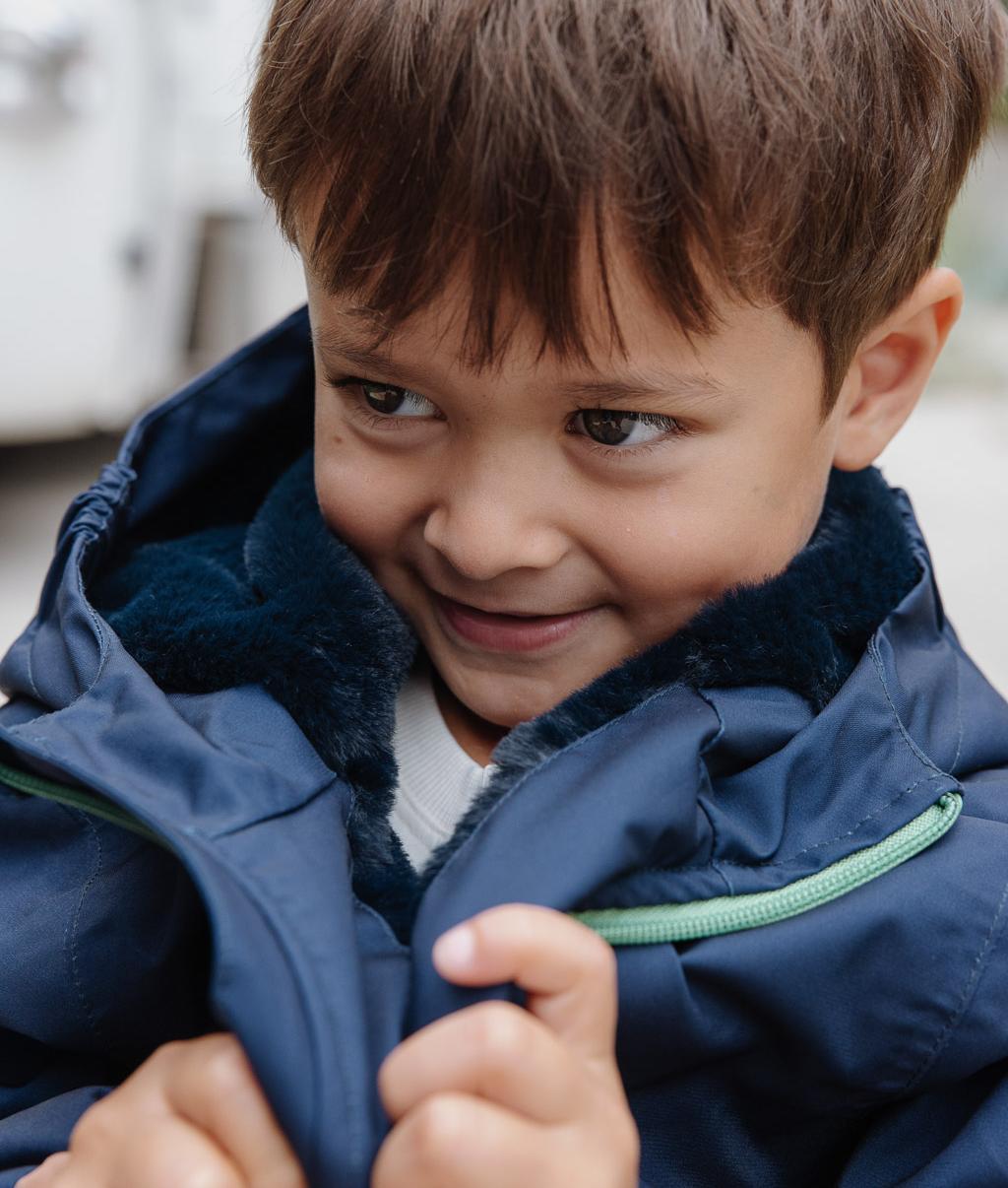 Kind trägt blaue Winterjacke mit Kunstfellfutter und Kapuze Hello Hossy