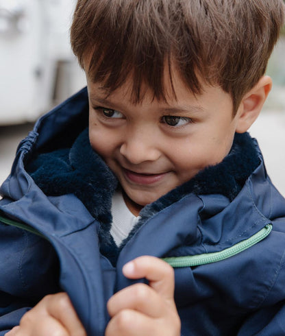 Kind trägt blaue Winterjacke mit Kunstfellfutter und Kapuze Hello Hossy